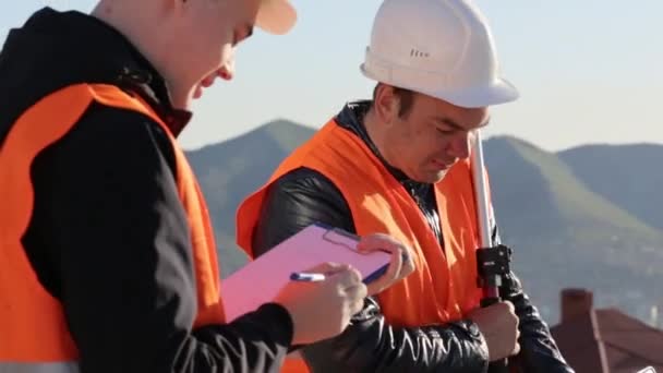 Vermessungsingenieure führen geodätische Messungen durch und fixieren sie auf Papier — Stockvideo