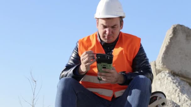 Geodesist sitting on the concrete plate and corecting data in geodetic device — Stock Video