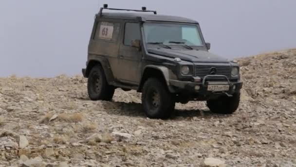 Car traveling on mountain road in a dry, desertic, landscape, near precipice. — Stock Video