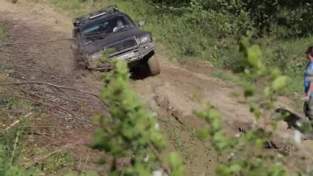 Expeditionary SUV riding on dirty road with ditchs and pits in the forest. — Stock Video