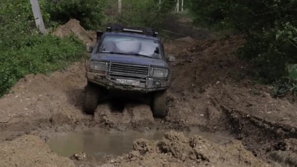 Expedicionaria SUV a caballo a través de trinchera profunda con agua sucia y escondites — Vídeo de stock