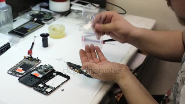 Master takes out part for repair cell phone and preparing it for installation — Stock Video