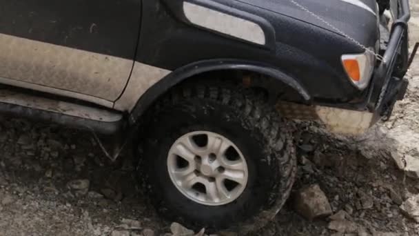 Primer plano video de SUV ejemplar paseos lentamente en el camino rocoso de montaña . — Vídeo de stock