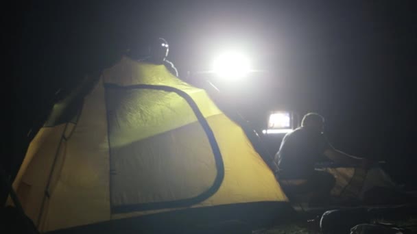 Noite tiro de dois homens erguendo tenda em ligh de SUV expedicionário . — Vídeo de Stock