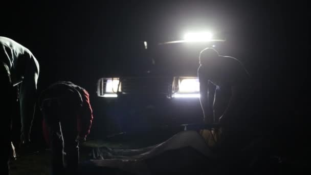 Disparo nocturno de dos hombres adultos y un niño erigiendo tienda en ligh de SUV . — Vídeos de Stock