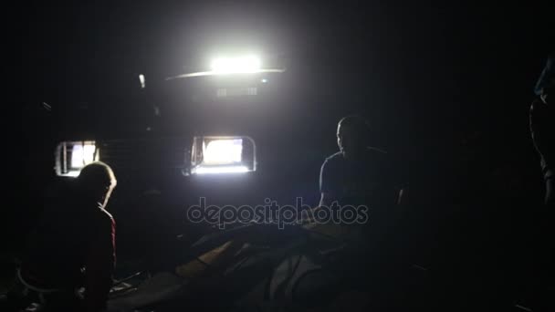 Nachtaufnahmen von zwei erwachsenen Männern und einem Kind beim Aufbau eines Zeltes aus einem Geländewagen. — Stockvideo