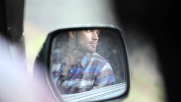 Reflection in side mirror of man sitting inside car and photographing — Stock Video
