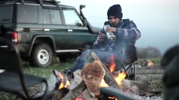 Podróżnik mężczyzna ubrany jak drwal stylu siedzi w pobliżu ogniska. — Wideo stockowe