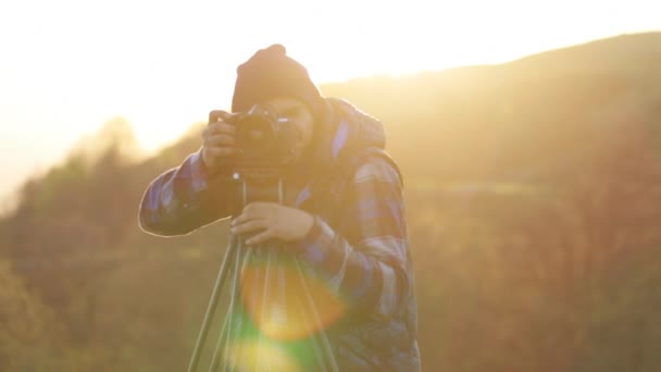 Fotograf, fotografování s kamerou a stativem na vrcholu kopce. — Stock video