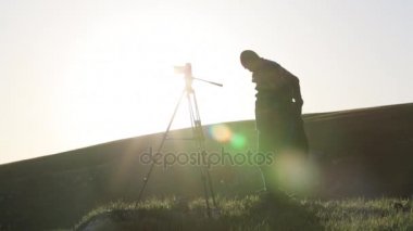 Kamera ve tepenin üst kısmında tripod ile çekim fotoğrafçı.