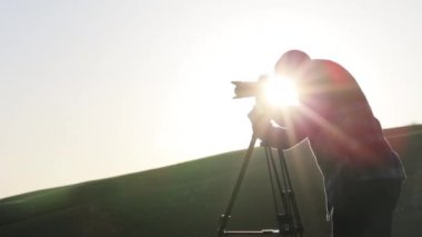 Kamera ve tepenin üst kısmında tripod ile çekim fotoğrafçı.