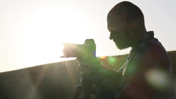 Fotograf, fotografování s kamerou a stativem na vrcholu kopce. — Stock video