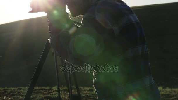 Фотограф снимает на камеру и штатив на вершине холма . — стоковое видео