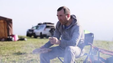 Kamp ateşi yanında kızarmış ekmek yeme üzgün erkekler