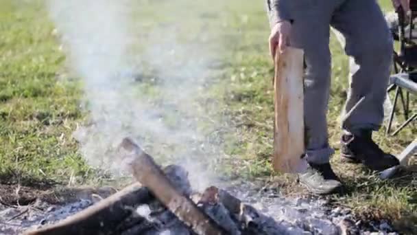 Male corrects coals in campfire — Stock Video