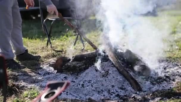 Male corrects coals in campfire — Stock Video