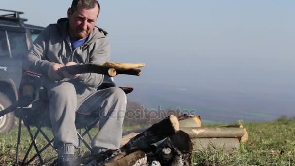 Männer sitzen am Lagerfeuer und braten Brot. — Stockvideo