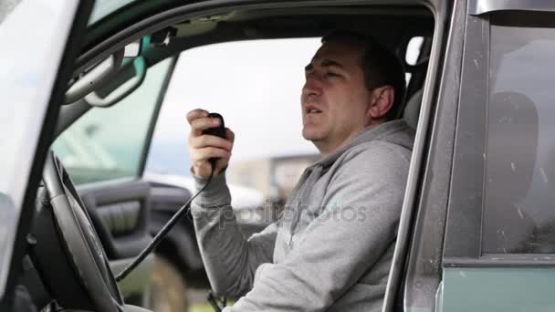 男子手持手麦克风和谈他的车里的收音机. — 图库视频影像