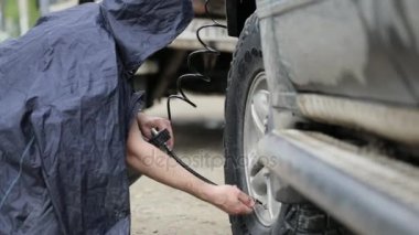 Erkekte Suv Jantlar yol kenarında pompalama yağmurluk