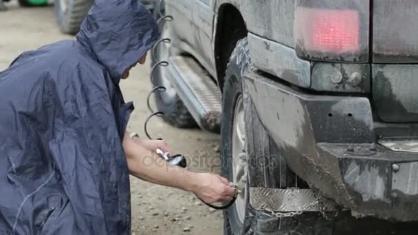 Hombre en impermeable ruedas de bombeo de SUV en carretera — Vídeos de Stock