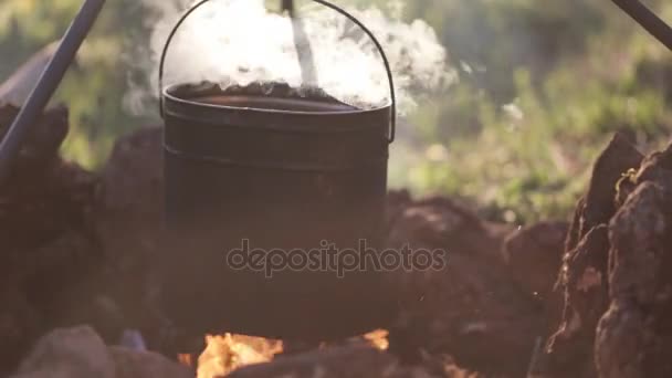 Γκρο πλαν του δοχείου με το φαγητό που κρέμεται πάνω από τη φωτιά — Αρχείο Βίντεο