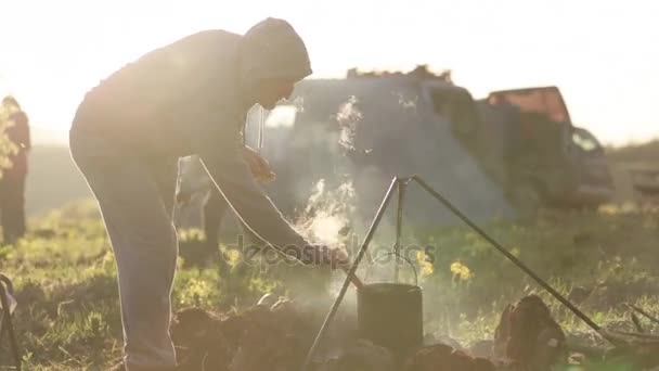 Kaukasische mannen koken voedsel in boowler op vreugdevuur op camping. — Stockvideo