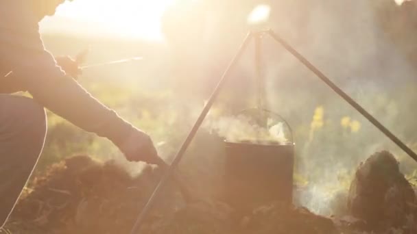 Caucasian men cooking food in boowler at bonfire in camping. — Stock Video