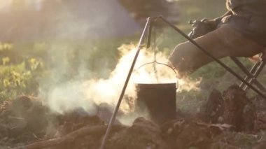 Profesyonel fotoğraf makinesi ile şenlik ateşi yanında oturan Gezgin.