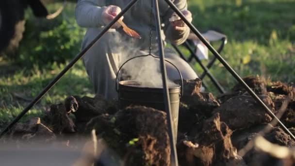 Caucásico hombres cocinar comida en boowler en hoguera en camping . — Vídeos de Stock