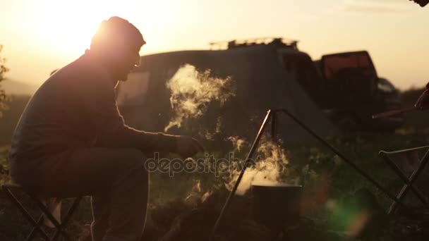 Padre con hijo cocinando comida en boowler en hoguera en camping . — Vídeo de stock