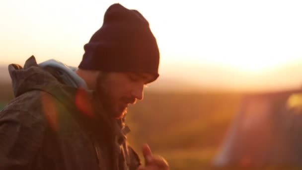 Porträt eines gutaussehenden Mannes mit Bart beim Zelten bei Sonnenuntergang. — Stockvideo
