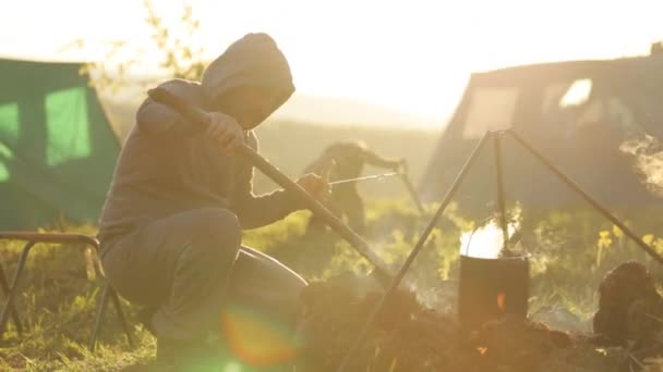 Kaukasische mannen koken voedsel in boowler op vreugdevuur op camping. — Stockvideo