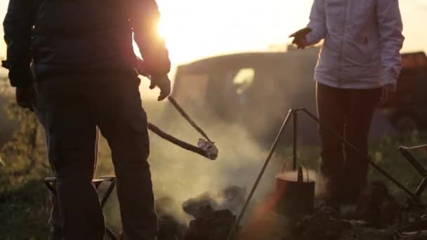 Group of people next to campfire at sunset, silhouette. — Stock Video