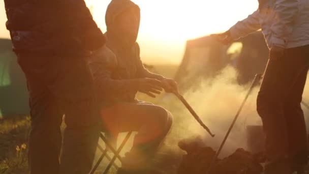 Groep mensen naast kampvuur bij zonsondergang, silhouet. — Stockvideo