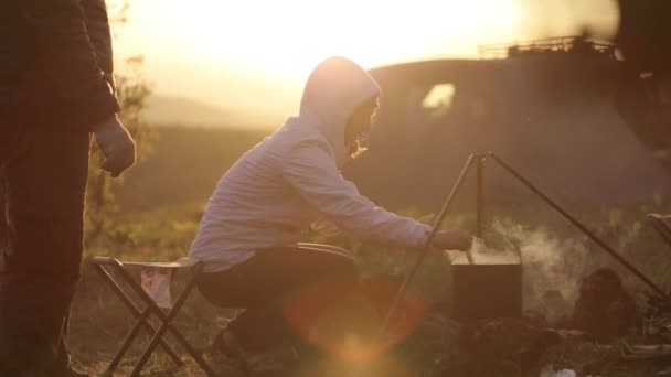 Family cooking dinner at the campfire at sunset. — Stock Video