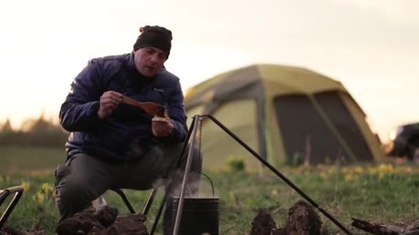 Hombres caucásicos en ropa de abrigo cocinando la cena en la fogata al atardecer . — Vídeo de stock