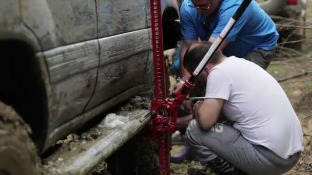 Dos viajeros reemplazando rueda de SUV expeditionaty en carretera sucia bosque . — Vídeos de Stock