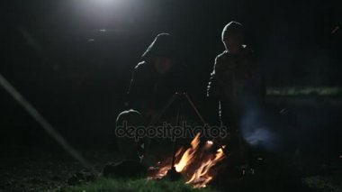 Baba ve oğul gece şenlik ateşi yanındaki silüeti.