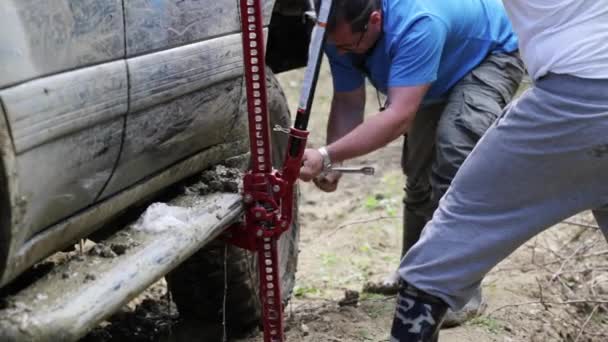 Two travelers replacing wheel of expeditionaty SUV at forest dirty road. — Stock Video