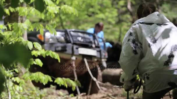 SUV kapott megragadt-on erdő és a népek csörlő segítségével legyőzni bonyolult terep. — Stock videók
