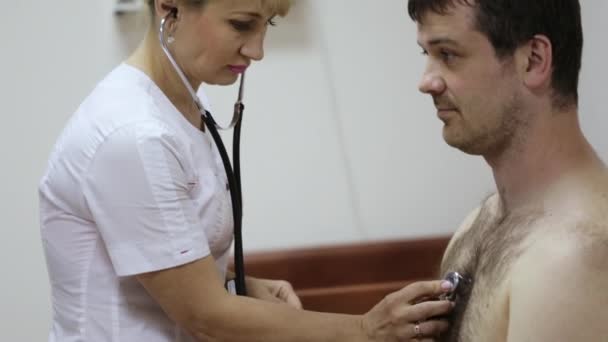 Verpleegkundige luistert naar een mannelijke patiënt via phonendoscope. — Stockvideo