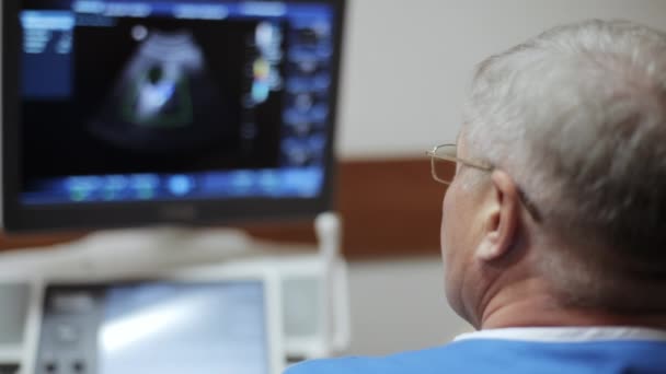 Médico varón que toma una ecografía del abdomen y mira en la pantalla — Vídeo de stock