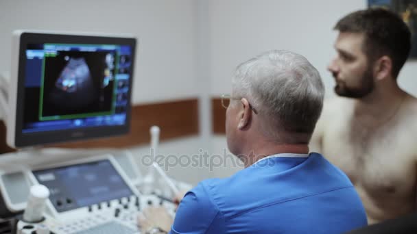 Доктор, що показує результати ультразвукової діагностики на екрані пристрою сонограми — стокове відео