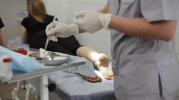 医師の診療所で女性患者の足に包帯を巻く. — ストック動画