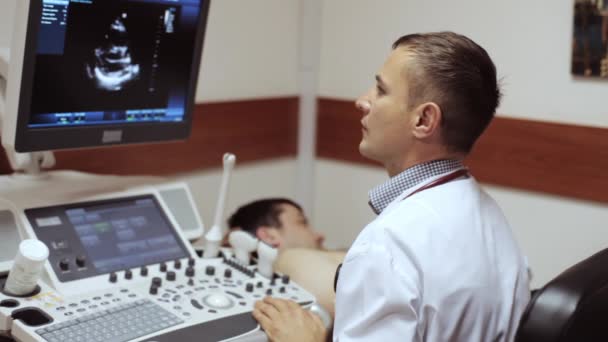 Médico tomando una ecografía y mirando en la pantalla del dispositivo de ultrasonido . — Vídeo de stock