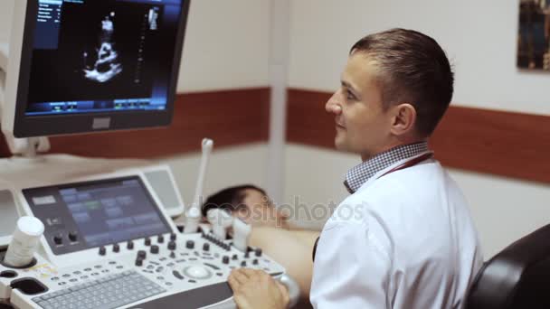 Médico fazendo um ultra-som e olhando na tela do dispositivo de ultra-som . — Vídeo de Stock