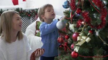 Genç ve güzel anne ile küçük oğlu Noel ağacı süsleme