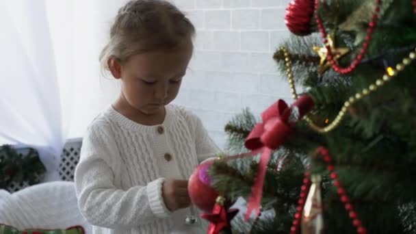 Petite fille mignonne décore le sapin de Noël .