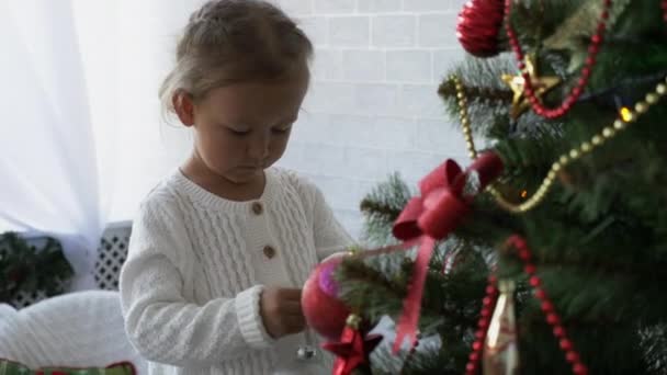 Nettes kleines Mädchen schmückt den Weihnachtsbaum. — Stockvideo