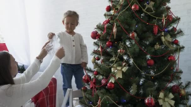 Мать и дочь украшают елку накануне новогоднего праздника — стоковое видео
